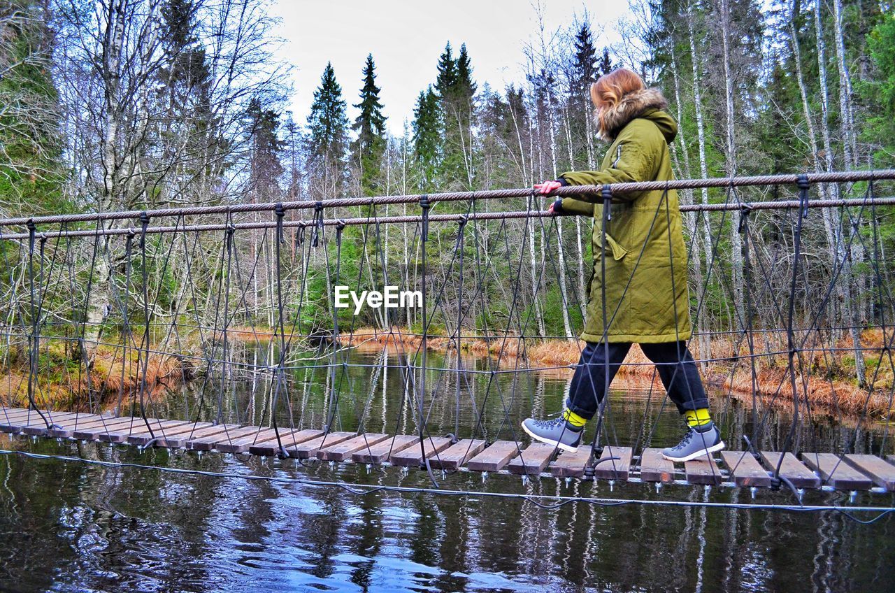 Woman walking on footbridge in forest