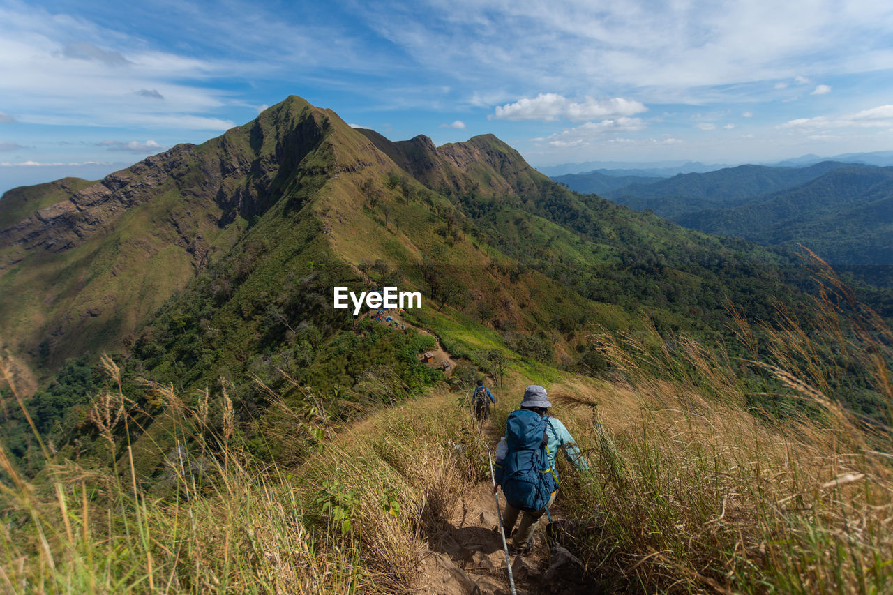 REAR VIEW OF MAN WALKING ON MOUNTAIN