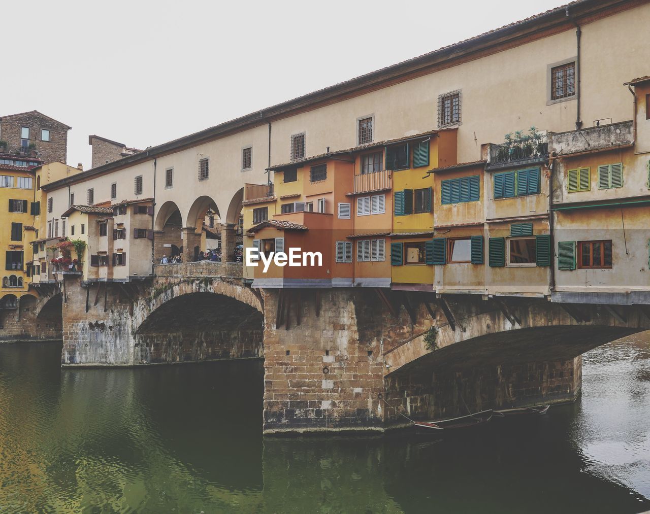 Bridge over river by buildings against clear sky