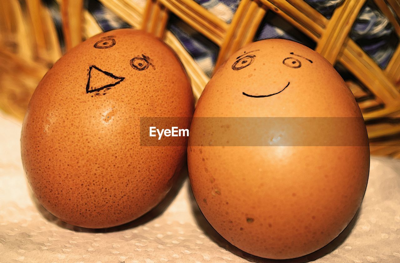 Close-up of anthropomorphic smiley faces drawn on brown eggs