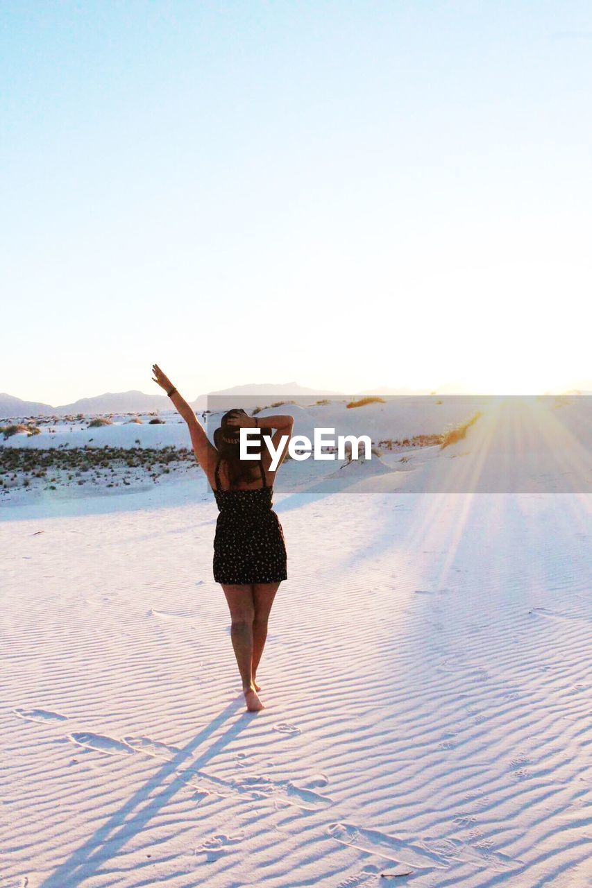 WOMAN STANDING ON BEACH AGAINST SKY