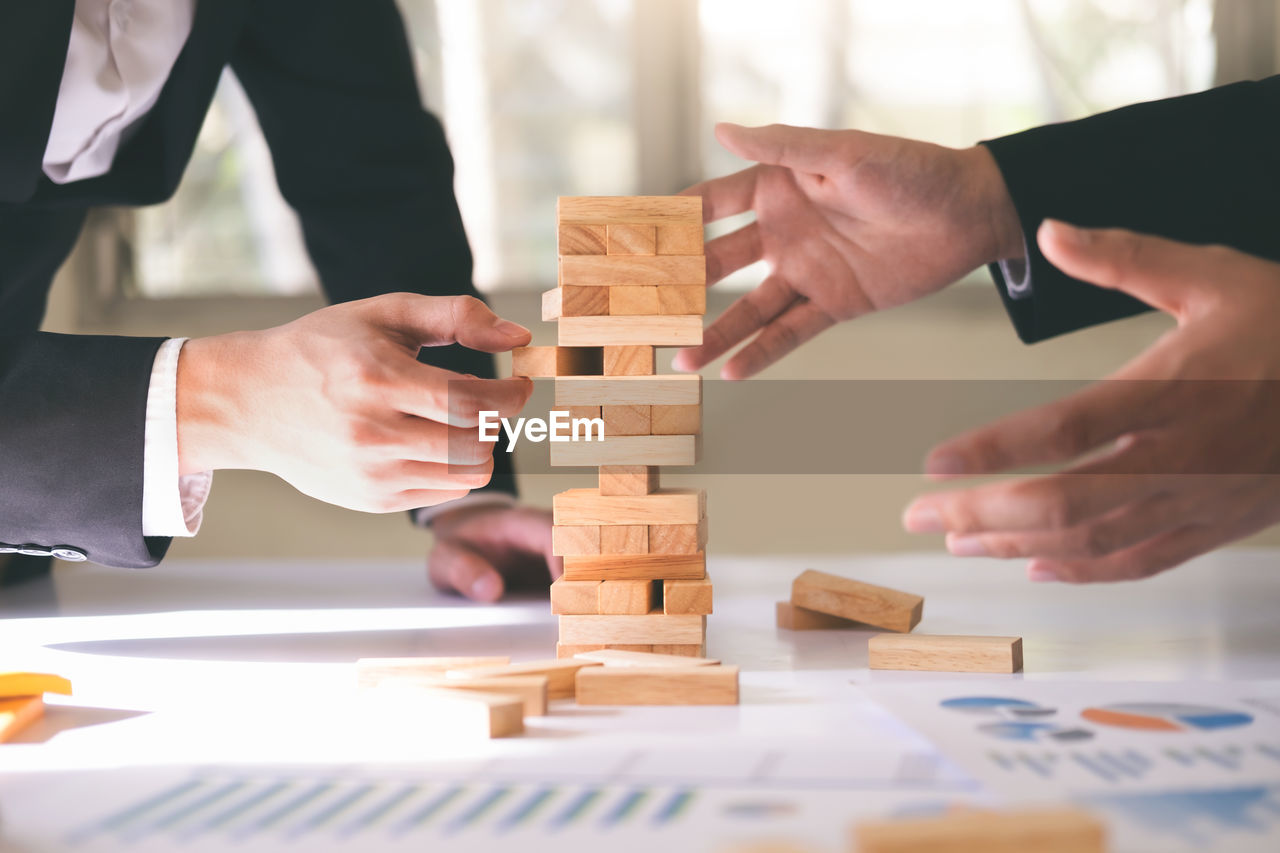 Midsection of businessman with colleague playing jenga