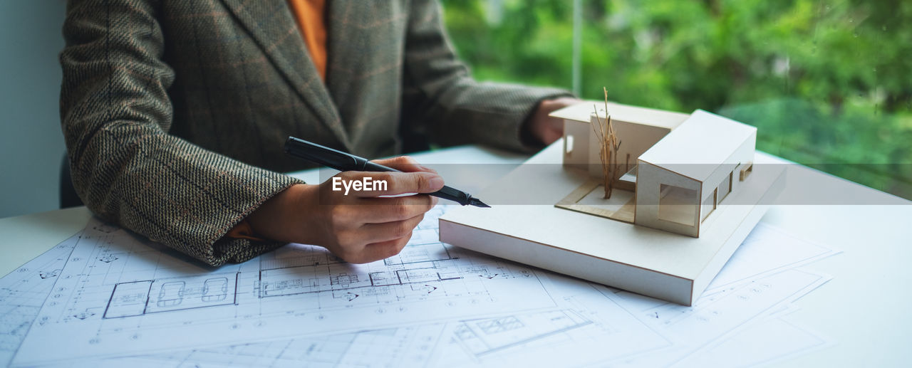 A female architect holding and working on an architecture house model 