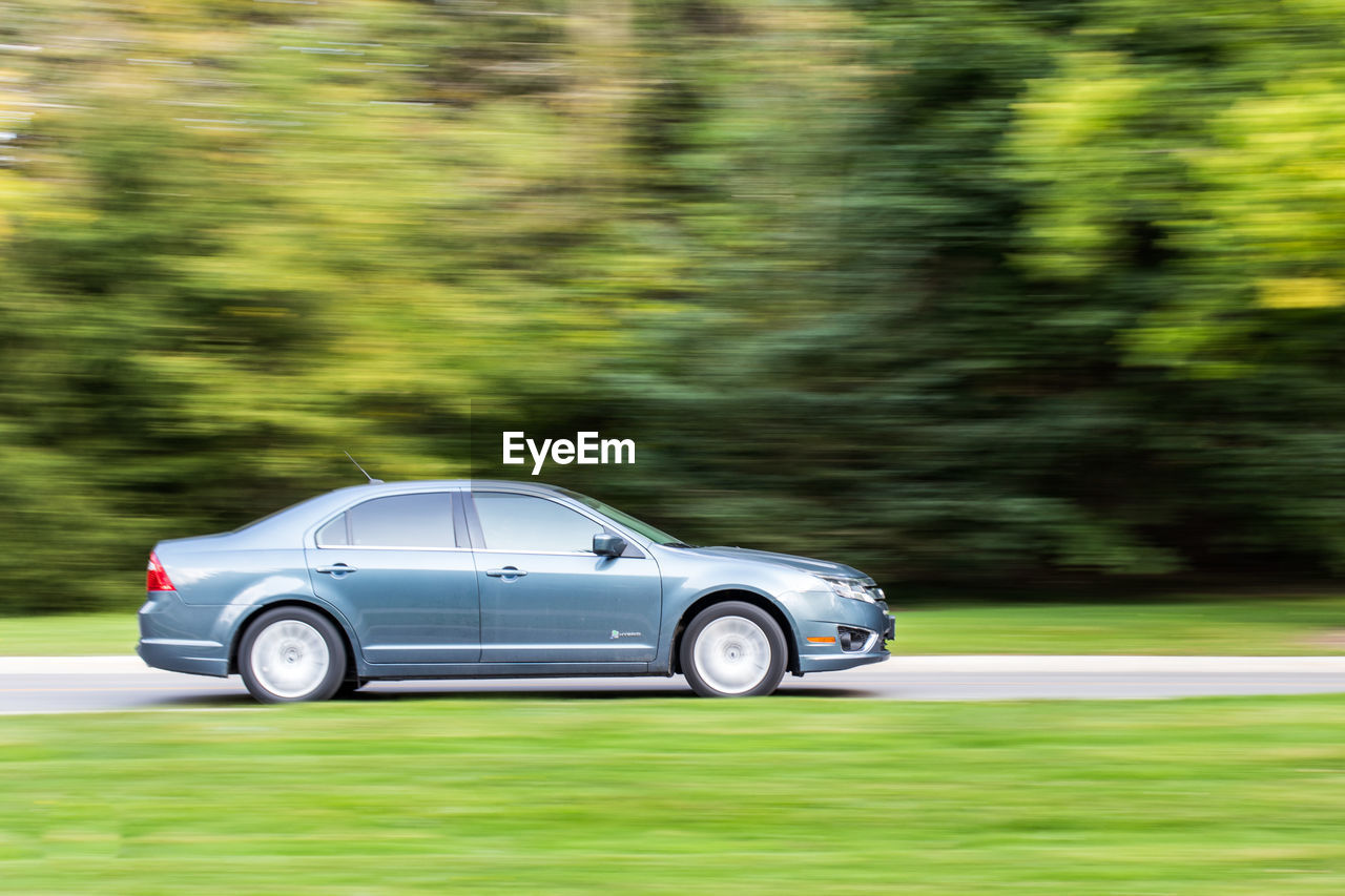 Modern car driving down country road