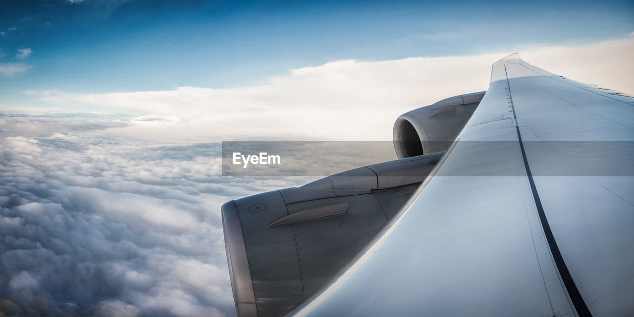 Cropped image of airplane wing over cloudscape