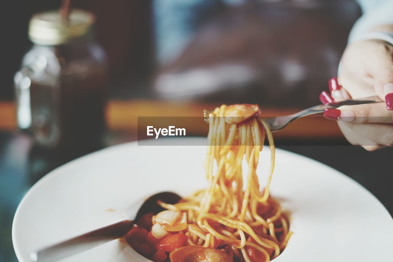 Cropped hand of woman having noodles in home