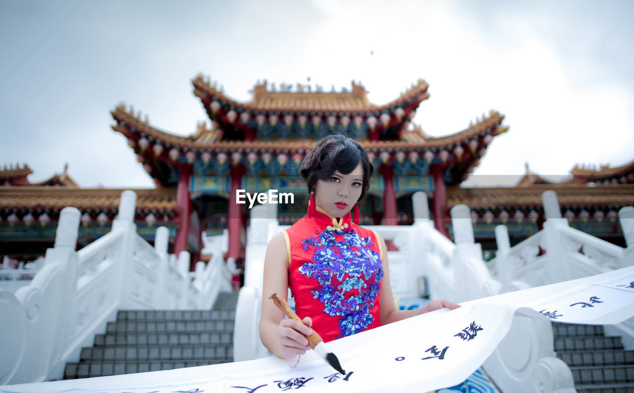 YOUNG WOMAN SITTING ON BUILDING