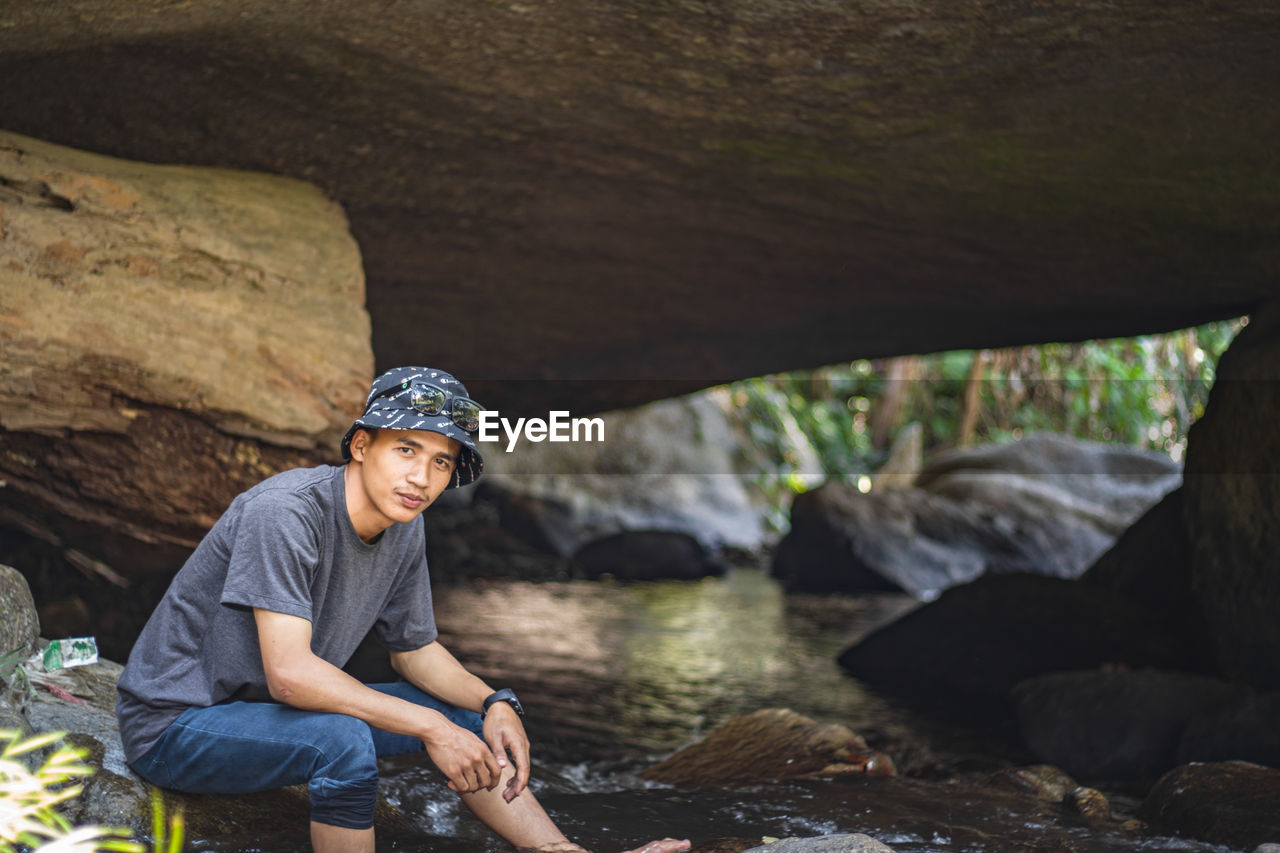 Portrait of young man sitting on rock