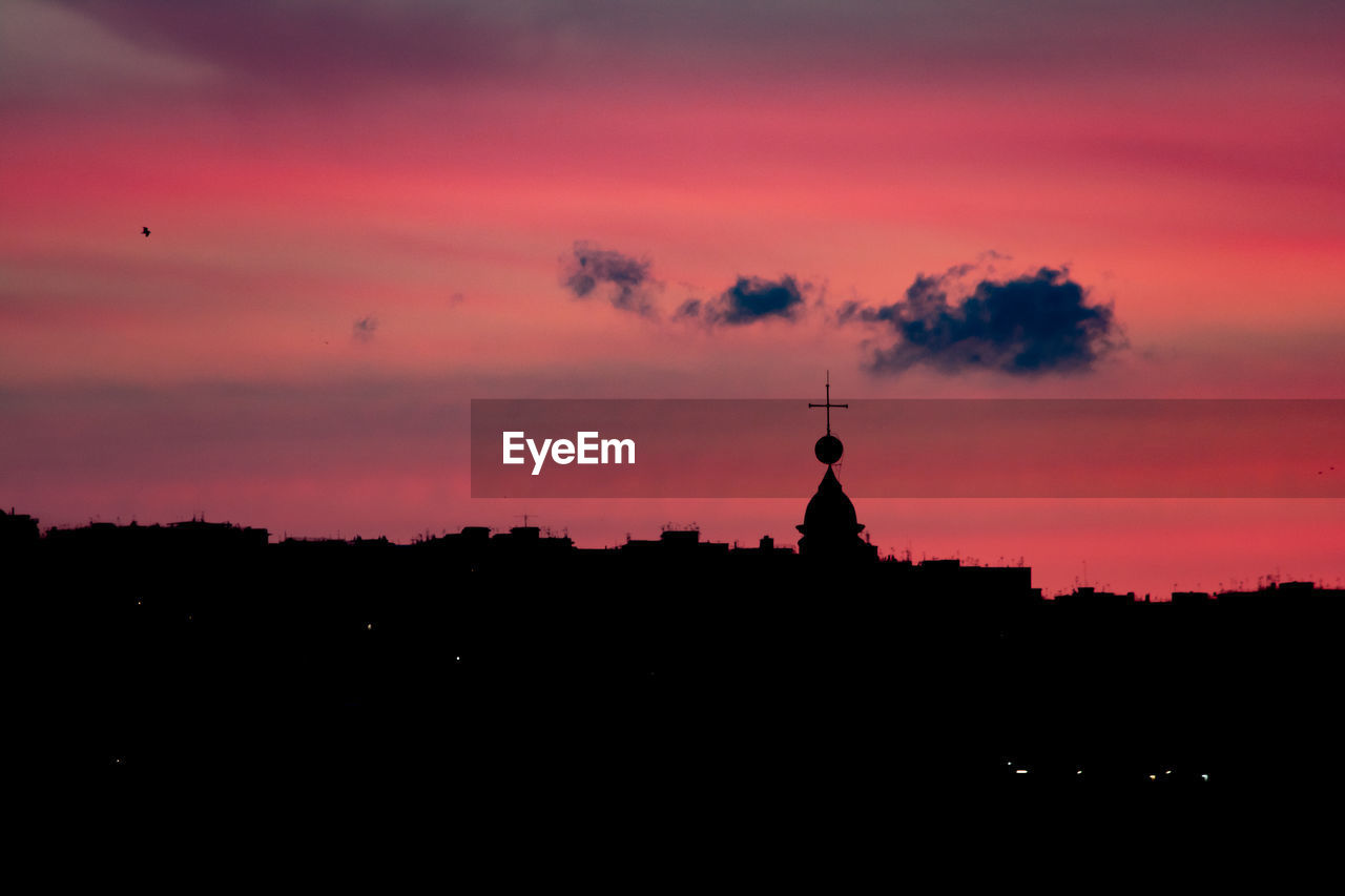 Silhouette of church against building during sunset