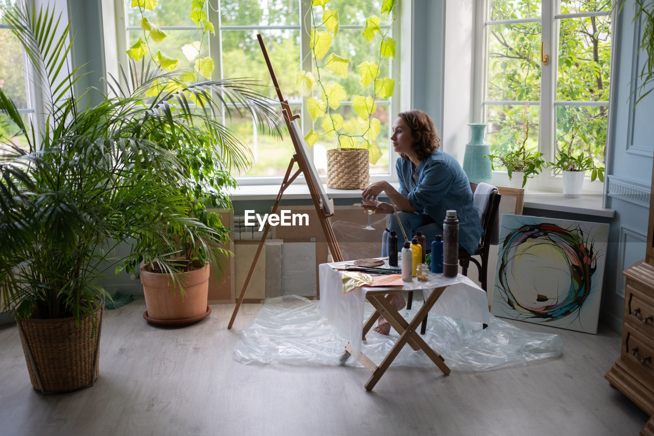 Artist with wine sitting near easel