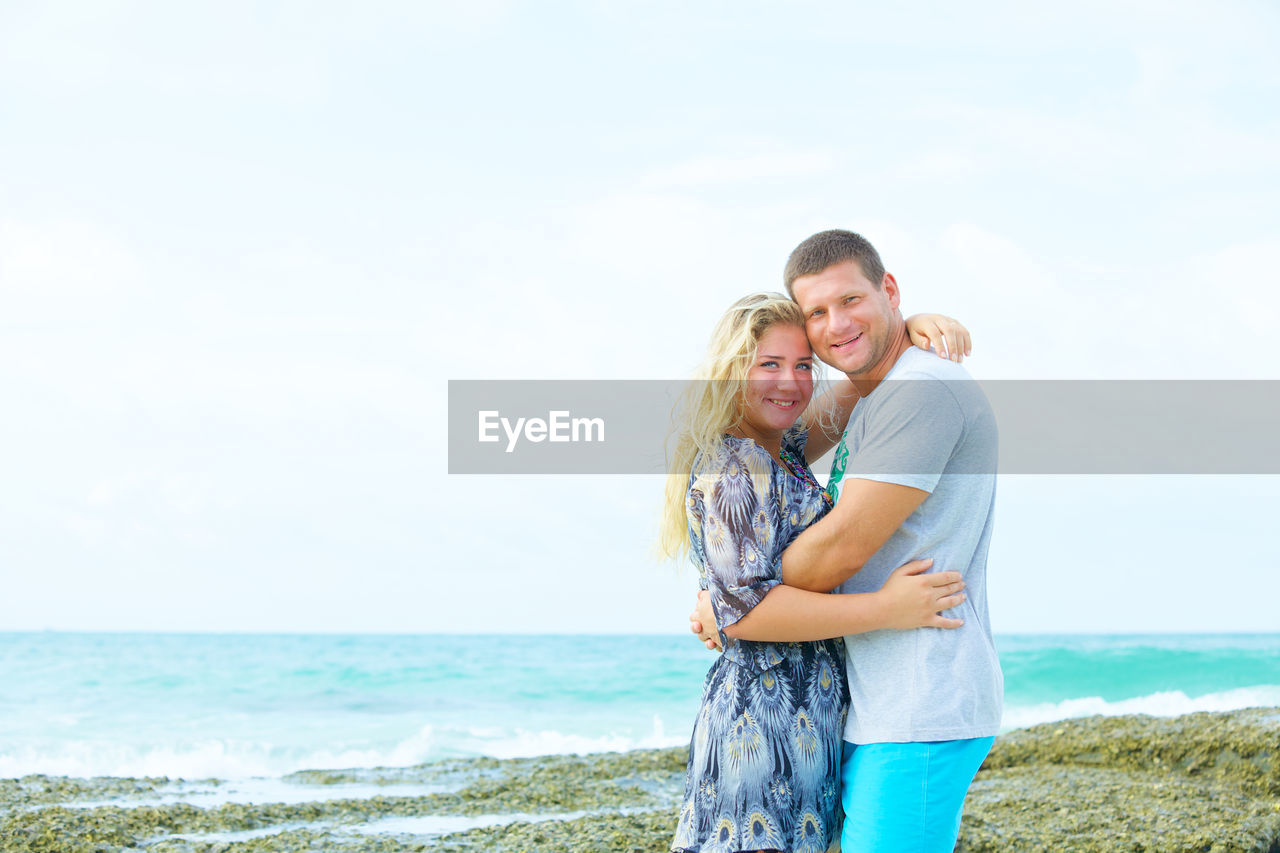 Portrait of a happy couple in love on the beach at summer day