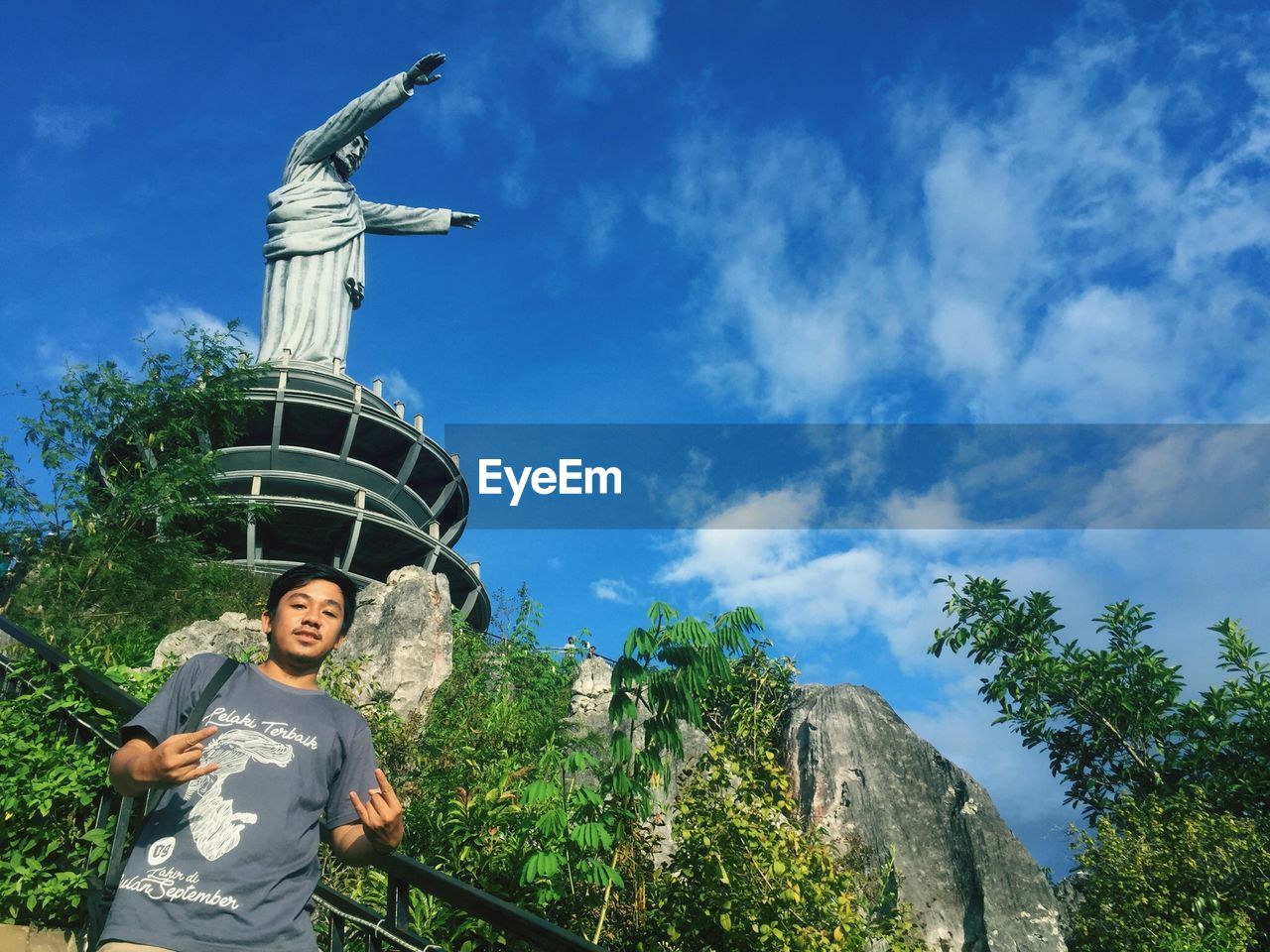 LOW ANGLE VIEW OF WOMAN STANDING AGAINST STATUE ON MOUNTAIN