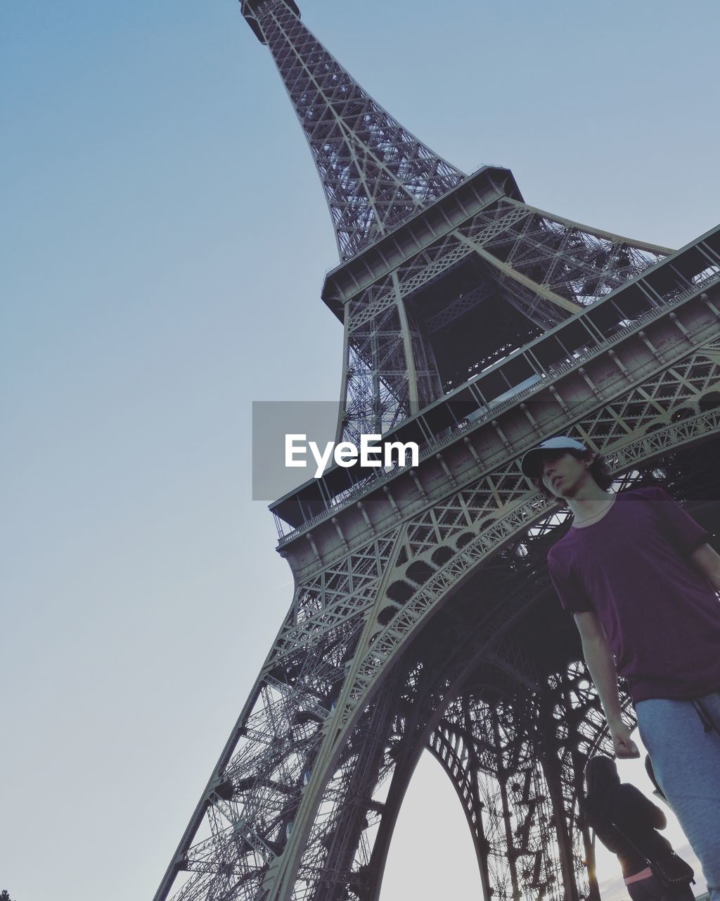 Low angle view of man standing against eiffel tower