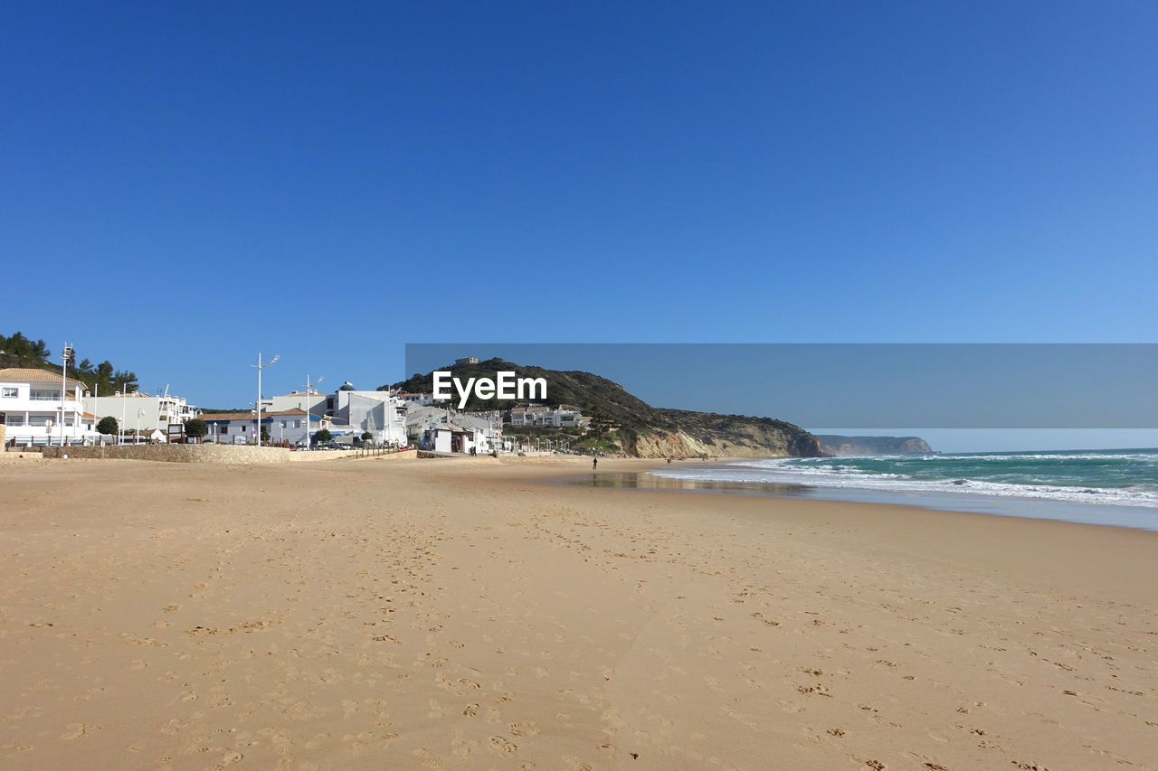 Scenic view of beach against clear blue sky