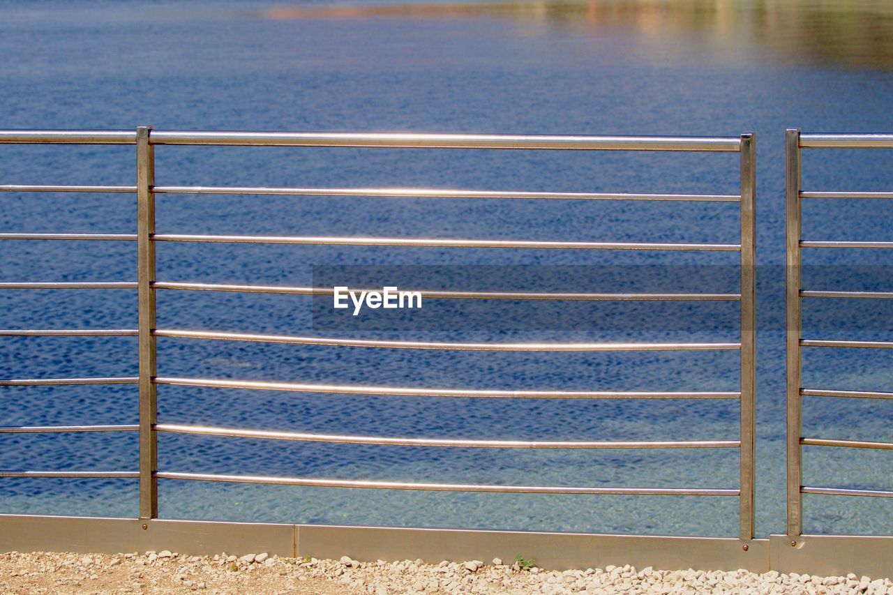 HIGH ANGLE VIEW OF METALLIC RAILING BY SEA