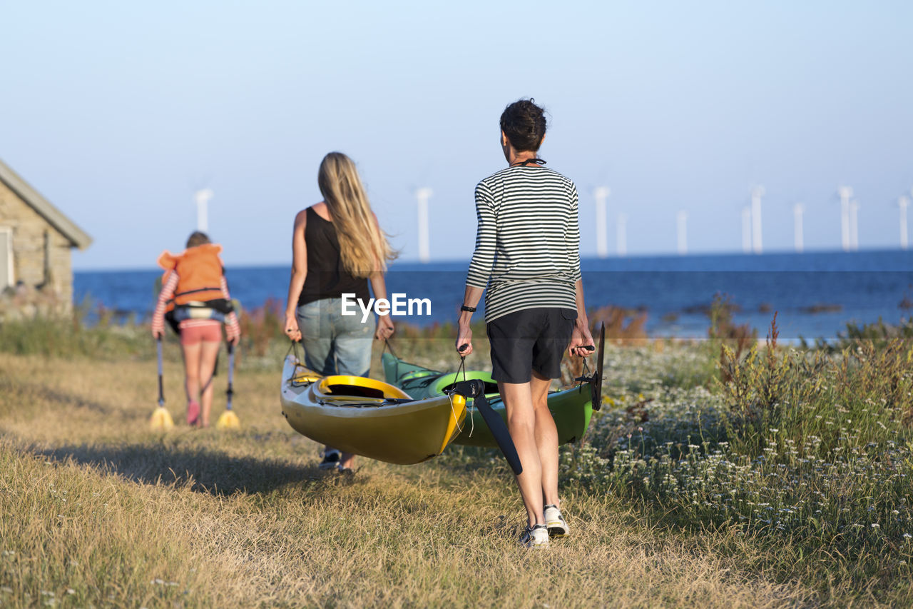 Mother with daughter carrying kayaks