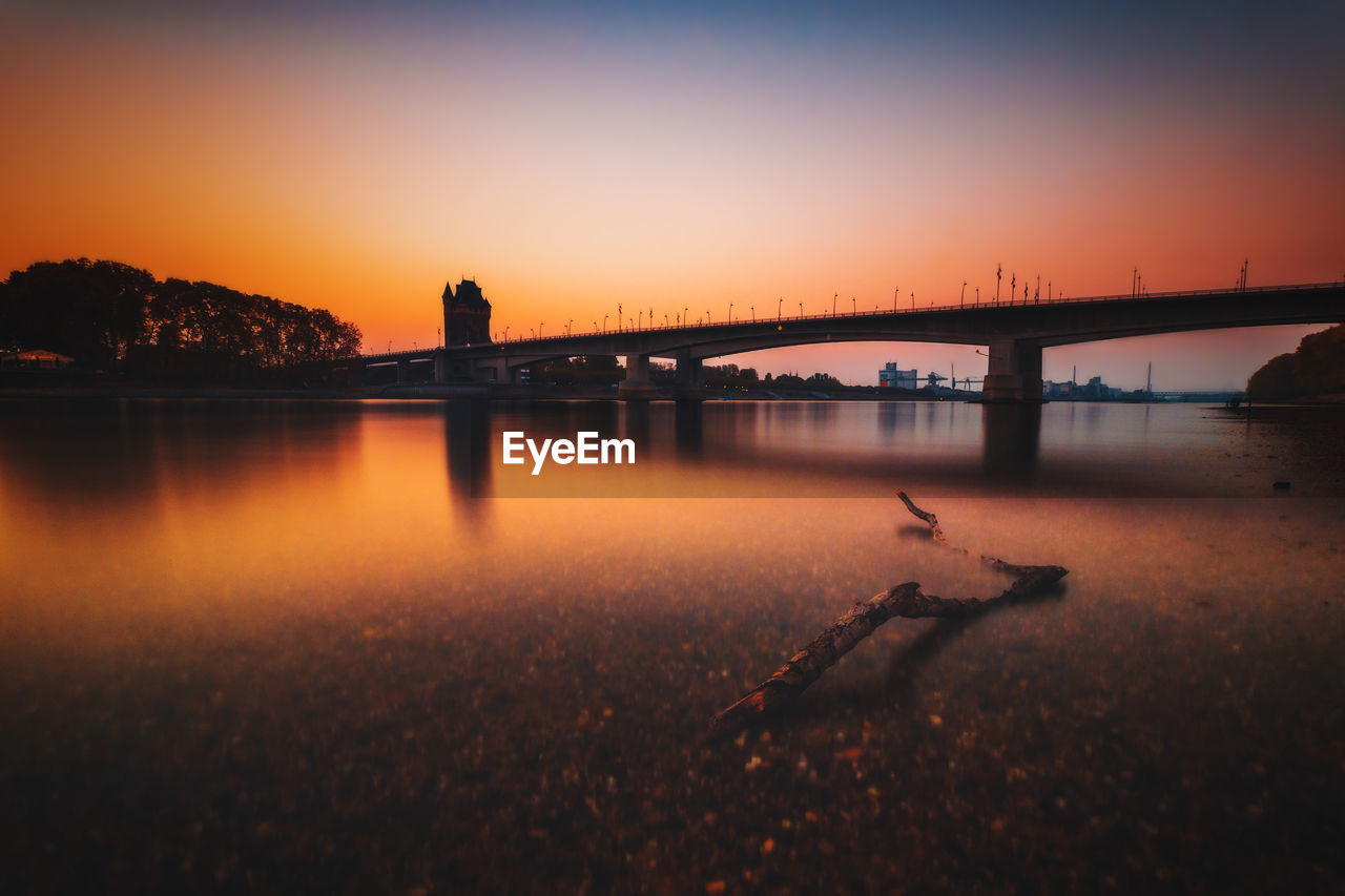 Bridge over river against sky during sunset