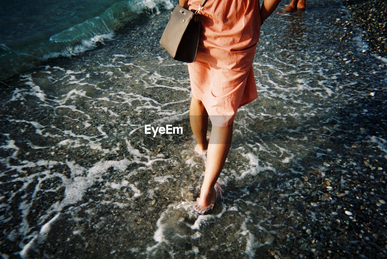 Low section of woman walking on shore at beach