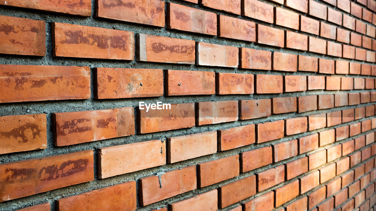FULL FRAME SHOT OF BRICK WALL WITH BUILDING