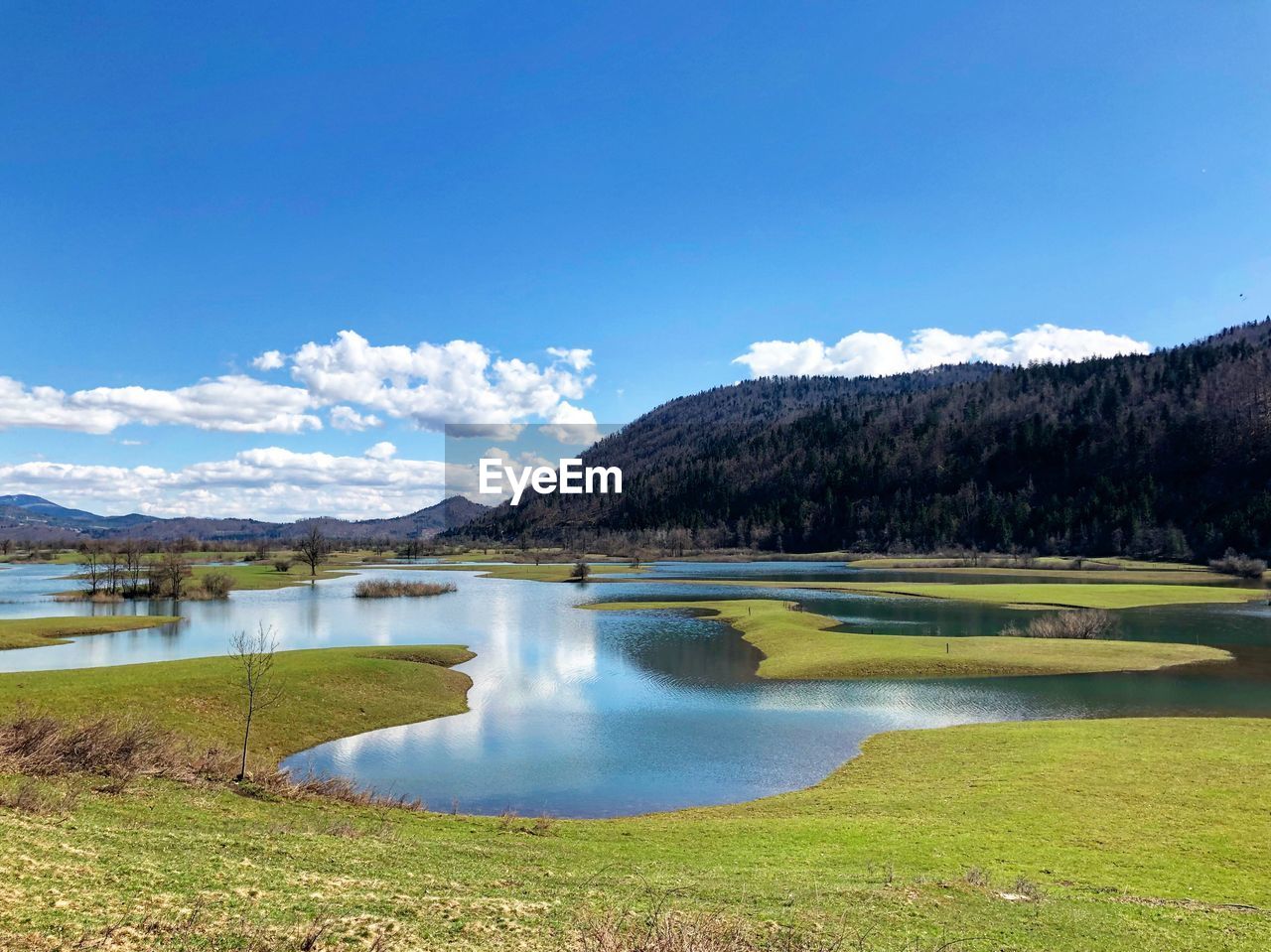 Scenic view of lake and mountains against blue sky