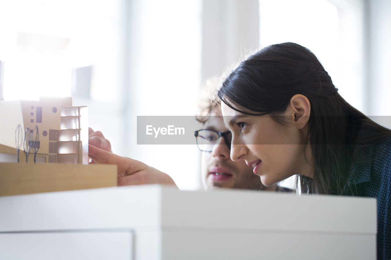 Man and woman discussing architectural model in office