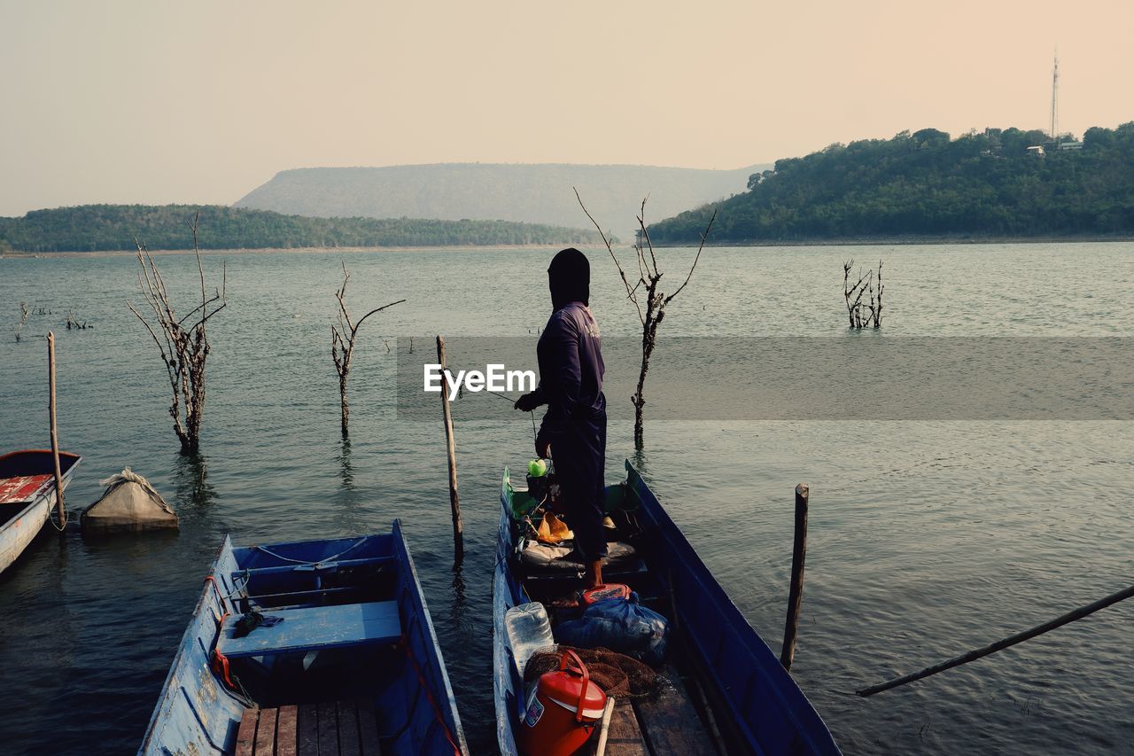 Rear view of man standing on sea against sky