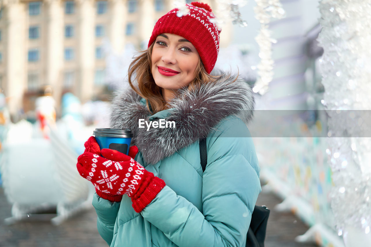 Portrait of smiling young woman wearing knit hat standing outdoors