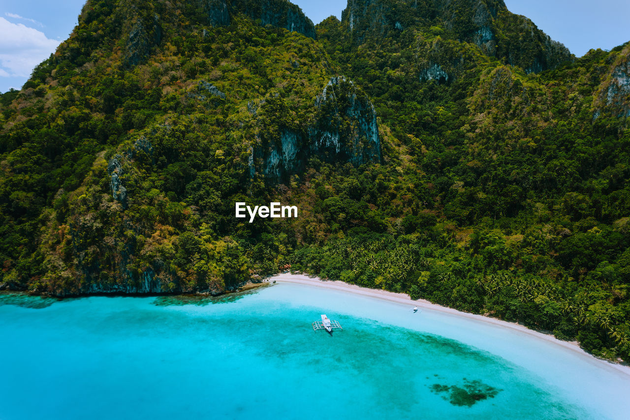 Scenic view of sea by tree mountain