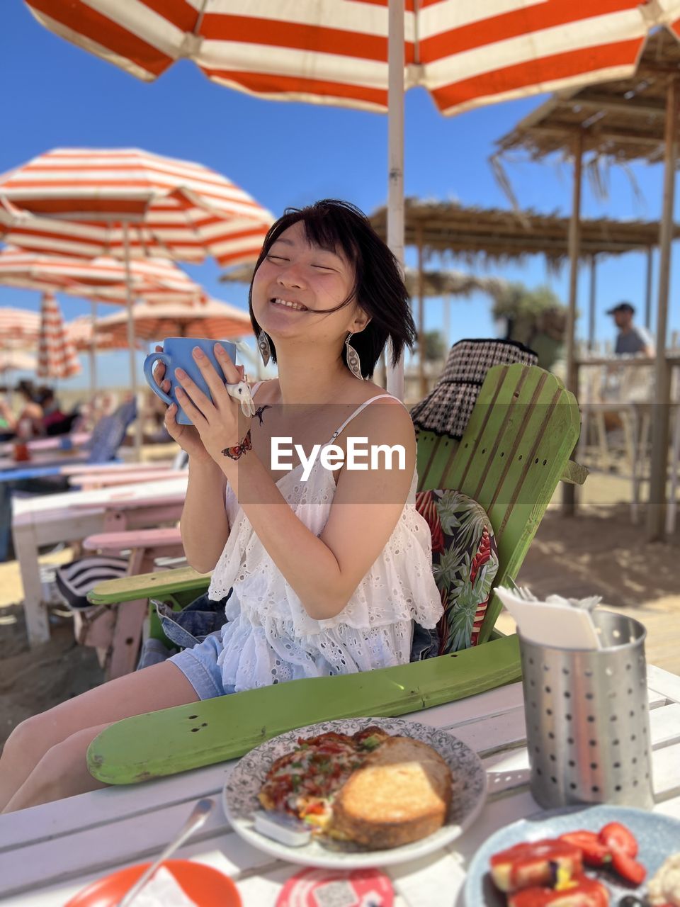 Smiling woman having food at the beach restaurant 