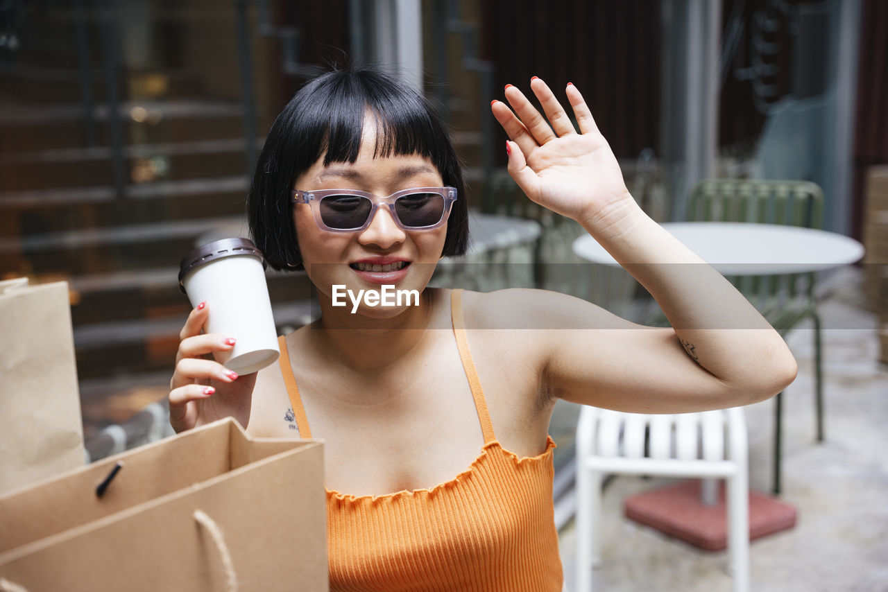 Lesbian woman holding disposable coffee cup sitting at cafe