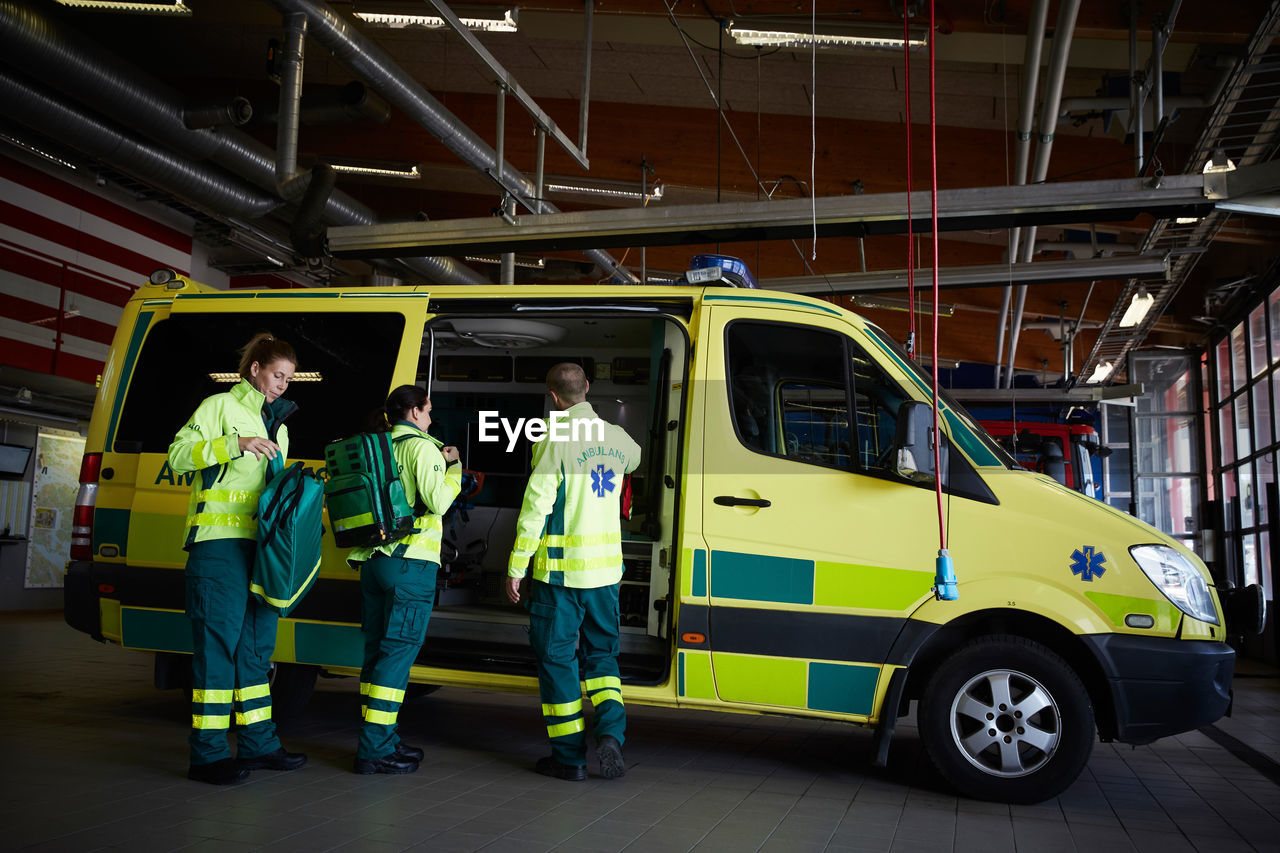 Full length of paramedics getting ready outside ambulance in parking lot