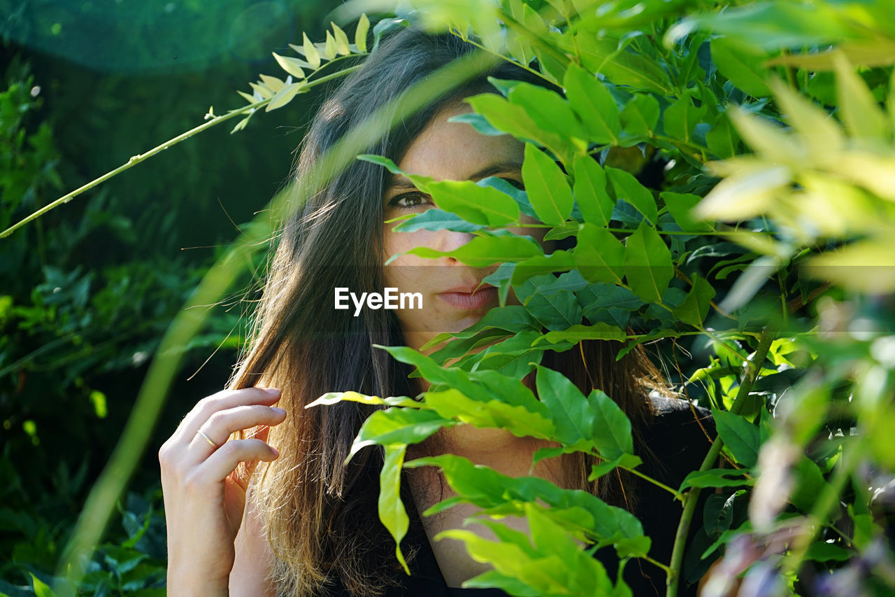 Portrait of young woman behind plants 