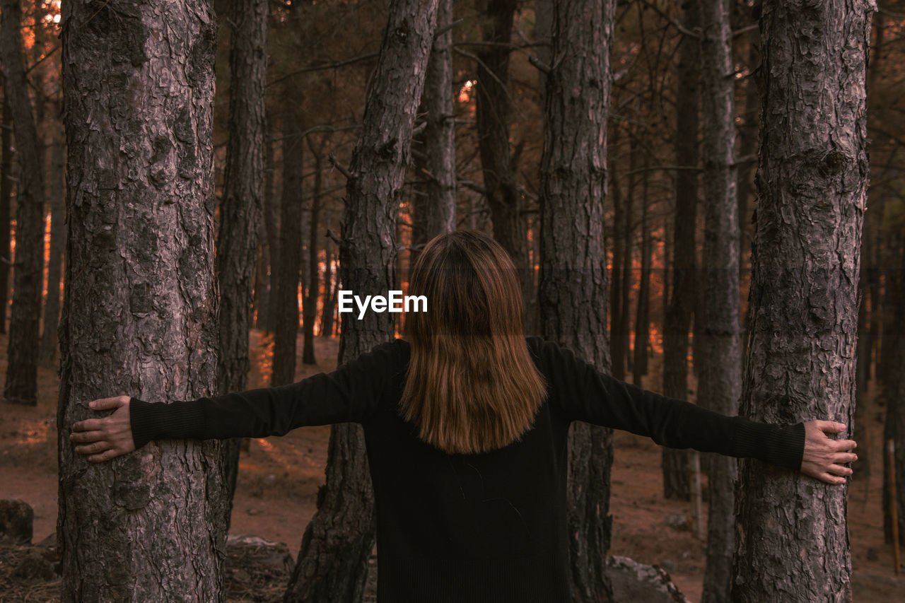 Rear view of woman standing in forest