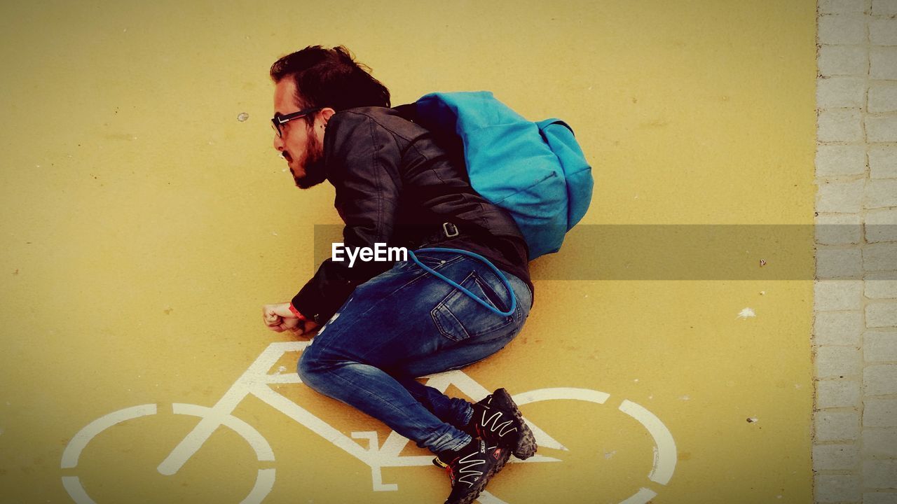 MIDSECTION OF MAN SITTING ON WALL