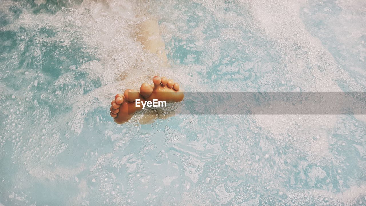 Low section of person swimming in pool