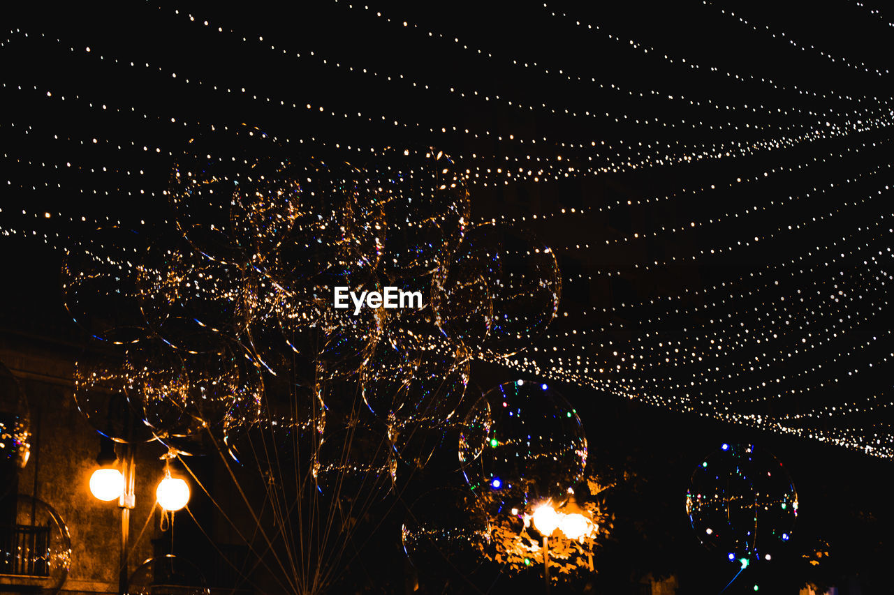 Low angle view of illuminated lighting equipment against sky at night