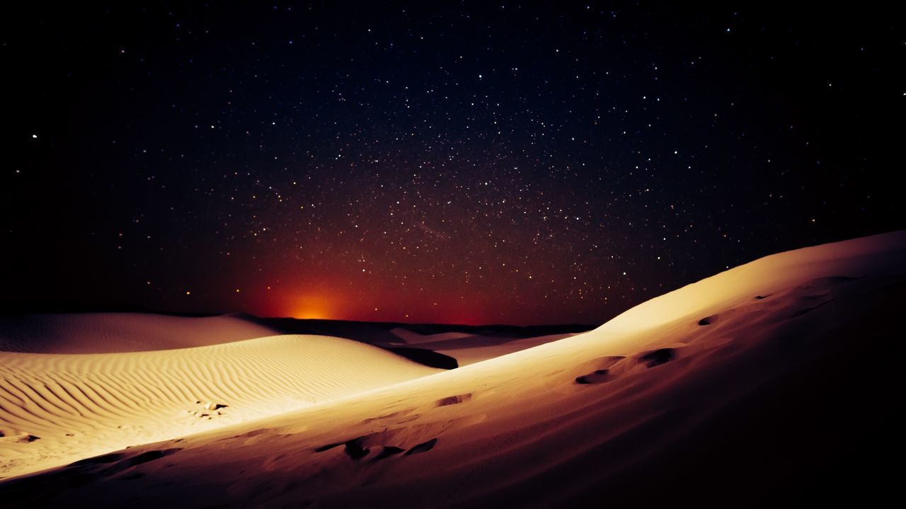 Scenic view of desert against star field sky at night