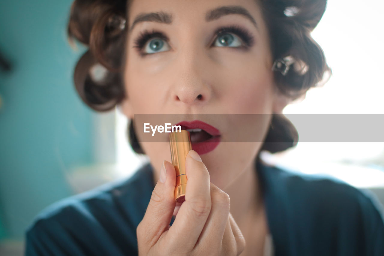 Close-up of woman applying red lipstick at home