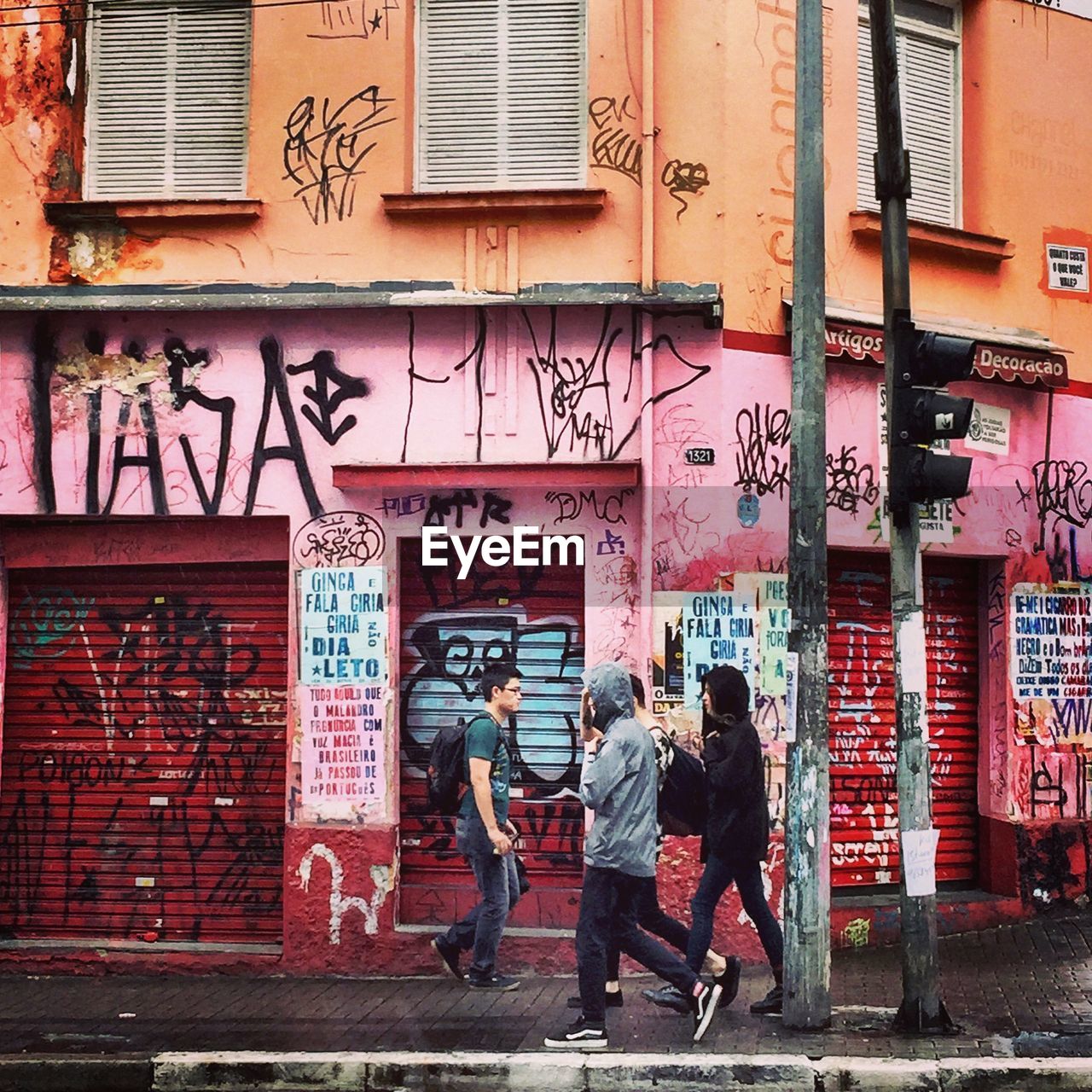 MAN STANDING IN FRONT OF GRAFFITI WALL