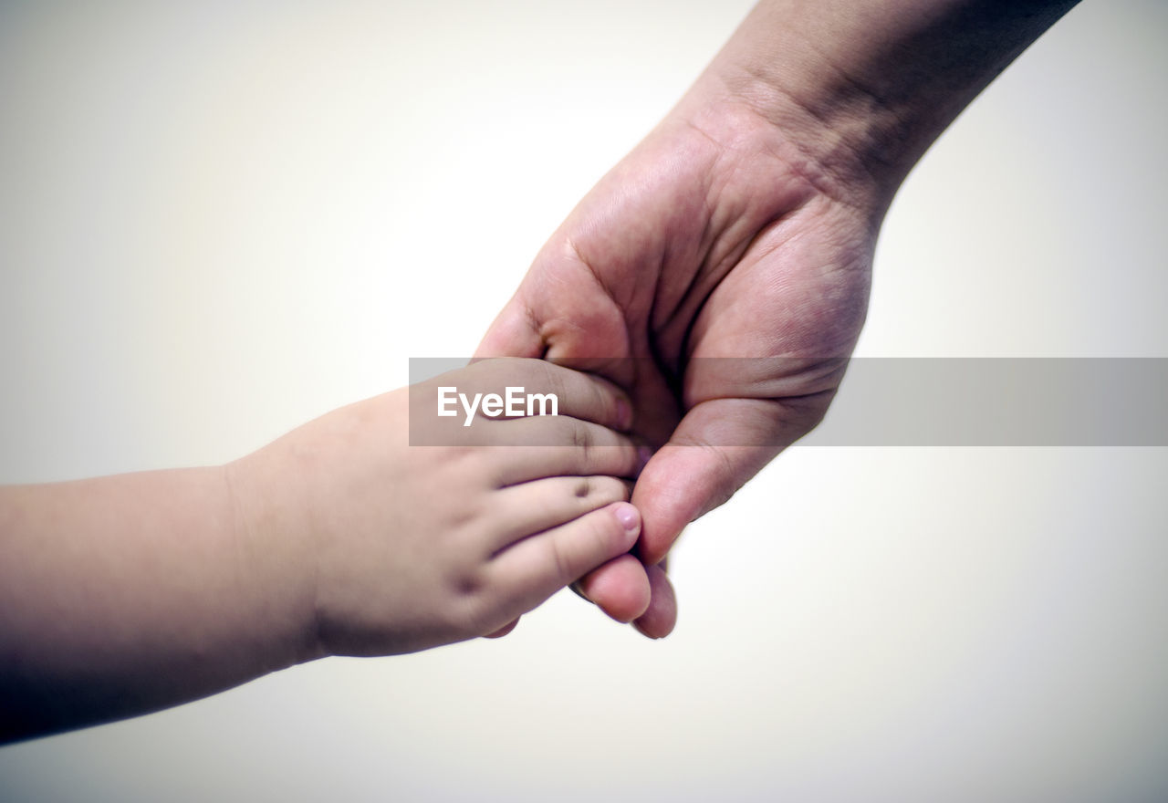 Close-up of people with holding hands against wall