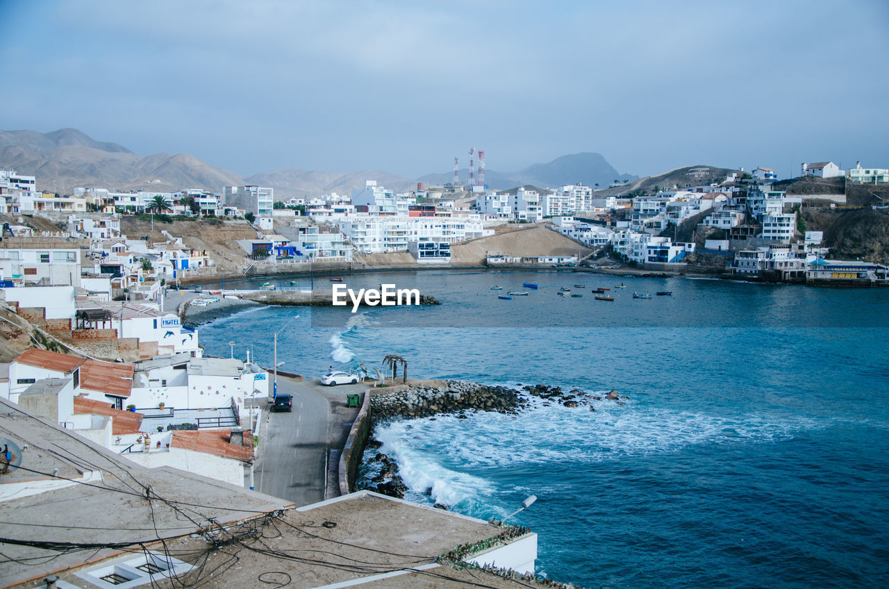 High angle view of townscape by sea against sky