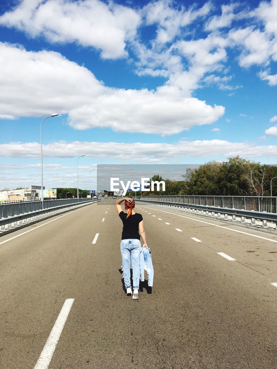 Rear view of woman standing on road against sky