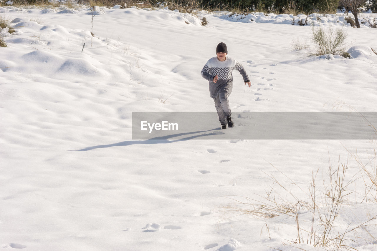 Child running in the snow on a sunny day,