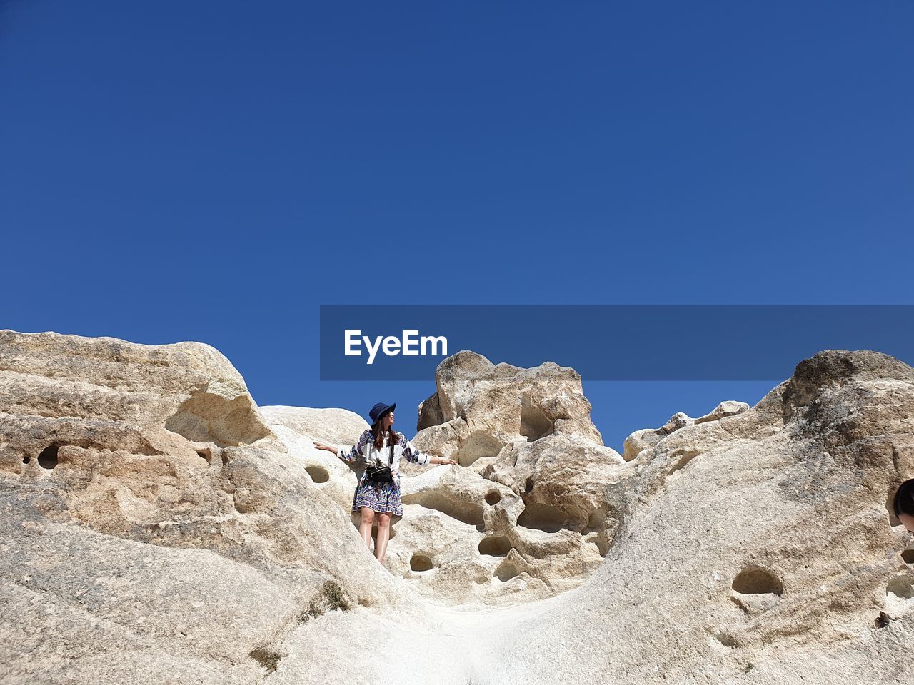 Low angle view of woman standing on rock against sky