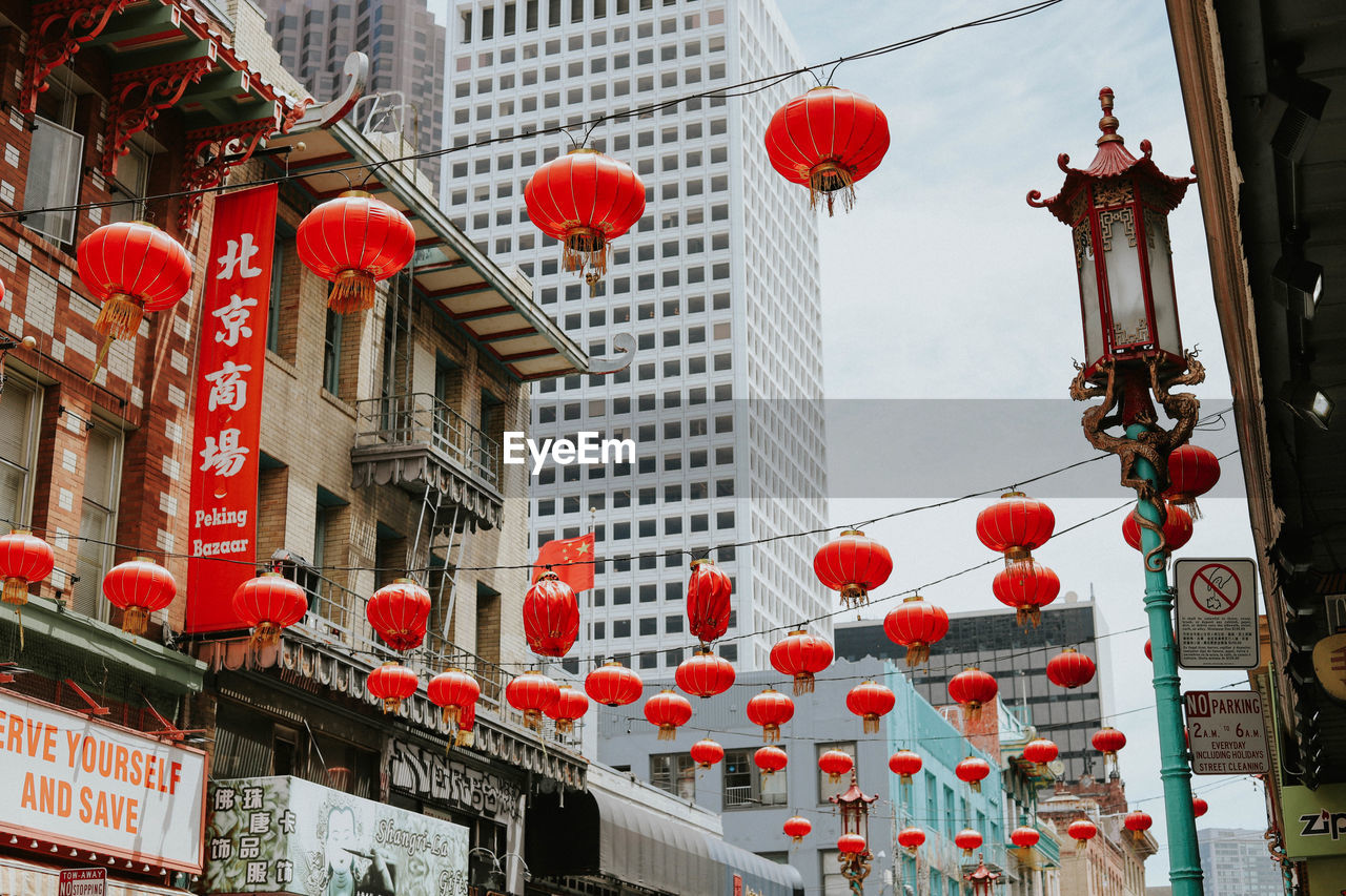 LOW ANGLE VIEW OF LANTERNS HANGING ON STREET BY BUILDINGS