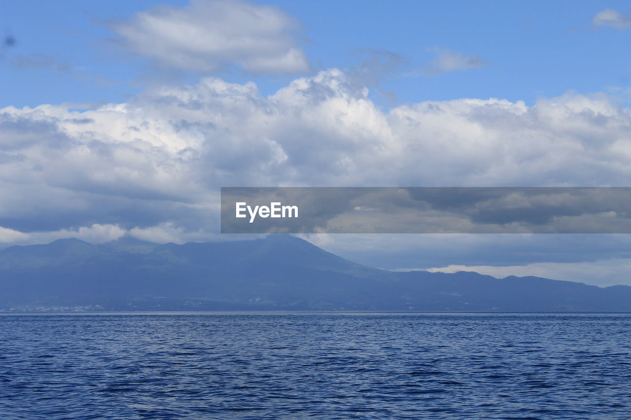 SCENIC VIEW OF SEA AND MOUNTAINS AGAINST BLUE SKY