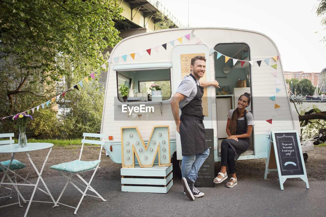 Portrait of happy male owner with female colleague outside food truck on street