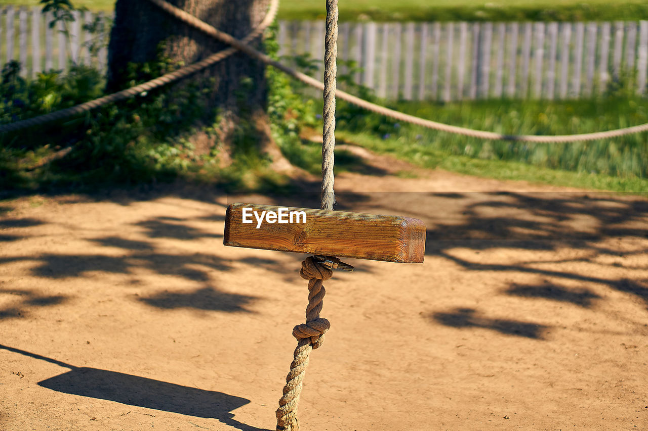 CLOSE-UP OF SWING HANGING ON METAL AT PARK
