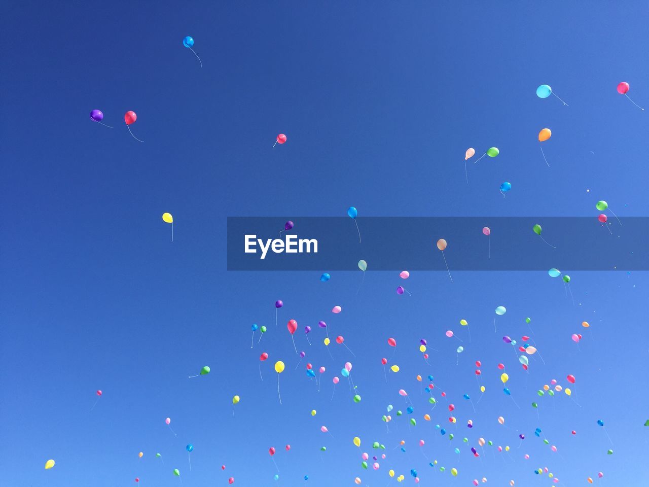 Low angle view of balloons flying against blue sky