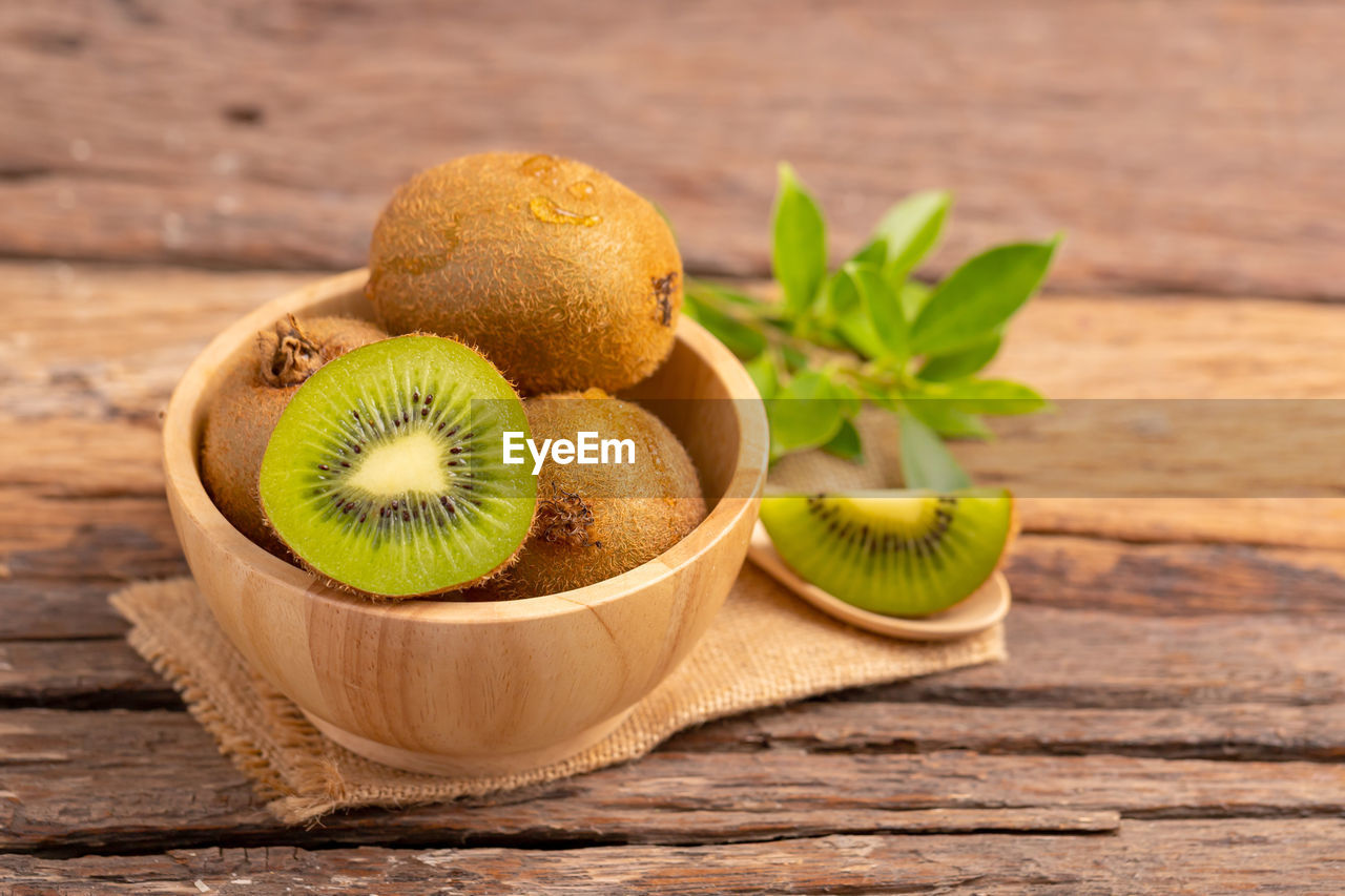 A half of kiwi in a wood bowl on the table.